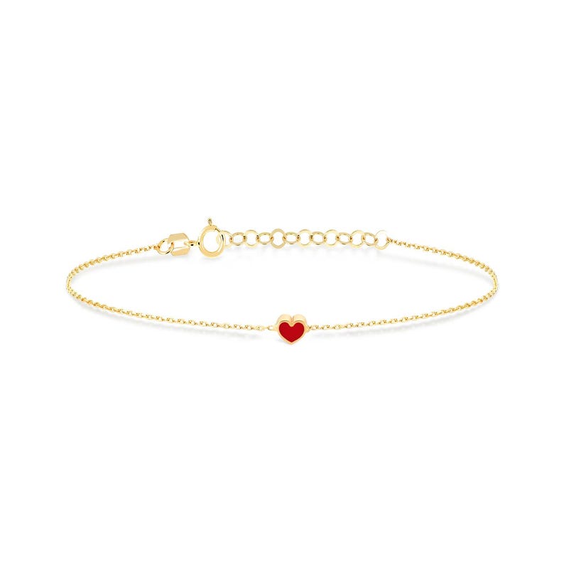 May include: Delicate gold bracelet featuring a small, vibrant red heart charm. The bracelet has a fine chain with an adjustable clasp. The heart charm is centered on the chain, creating a simple yet elegant design.