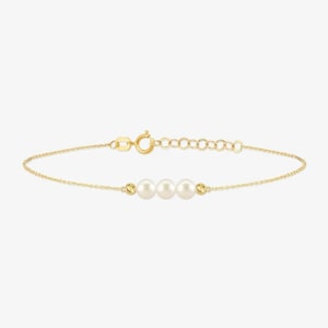 May include: A delicate gold chain bracelet featuring three centered white pearls and two small gold beads. The bracelet includes a lobster claw clasp and an adjustable extender chain with several circular links for a customizable fit.