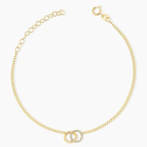 May include: A gold chain necklace featuring two interlocking circular pendants at the center. One pendant is a plain polished gold ring, while the other is a gold ring encrusted with small clear stones. The necklace includes a lobster claw clasp.