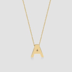 May include: A gold-toned necklace featuring a pendant shaped like the capital letter A. The pendant is suspended from a delicate, thin gold-toned chain with small, uniform links. The letter A has a smooth, polished surface and a clean, geometric design.