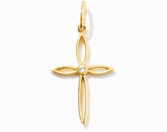 May include: A gold cross pendant featuring four elongated, open-work petal-shaped arms that meet at a central point. A single, small, clear round gemstone is set at the center of the cross, and a small gold jump ring is attached to the top.