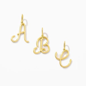 May include: Three gold-toned metal letter pendants featuring the cursive characters A, B, and E. Each pendant has a small loop at the top for attachment, showcasing a polished, reflective surface and elegant, flowing script typography.