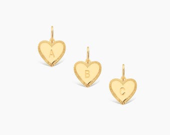 May include: Three gold heart-shaped charms, each featuring a textured, ribbed border and a central engraved letter. The charms are arranged diagonally, displaying the letters A, B, and C respectively, with a small jump ring at the top of each.