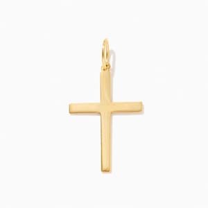 May include: A polished gold cross pendant featuring a smooth, flat surface and clean, straight edges. The pendant includes a small, circular jump ring at the top for attachment to a chain, showcasing a simple, uniform design with a reflective finish.