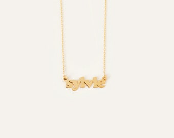Puede incluir: Collar de oro con el nombre "Sylvie" escrito en una fuente en negrita y estilizada.