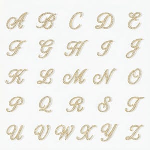 May include: A collection of gold-colored, cursive letter charms, each encrusted with small, sparkling stones. The letters A through Z are displayed against a white background. The charms are arranged in rows and columns.