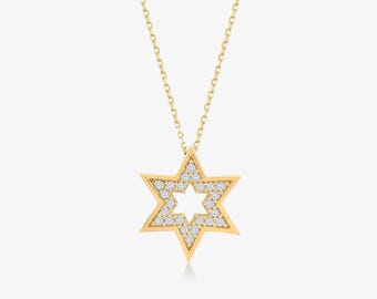 May include: A gold necklace featuring a six-pointed Star of David pendant. The pendant is crafted with a polished gold frame and is inlaid with small, clear, round-cut stones along the star shape, suspended from a delicate gold chain.