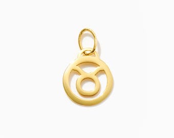 May include: A polished gold-tone metal pendant featuring the Taurus zodiac symbol. The circular charm has a cutout design representing the bull's head and horns, topped with a small, integrated oval jump ring for attachment to a necklace chain.