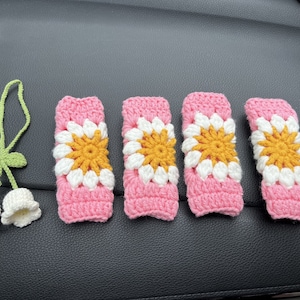 May include: Five crocheted pink and white car seat covers with yellow flower accents.