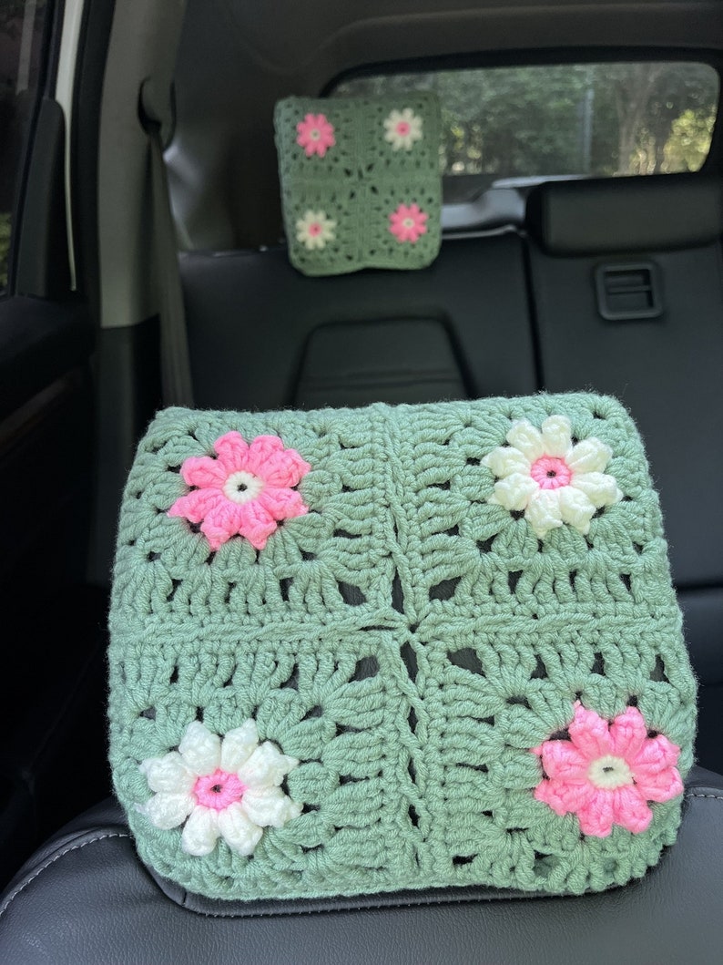 May include: Two crocheted headrest cushions for car seats. The cushions are green with white and pink flowers.