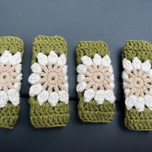 May include: Four crocheted green and white flower-shaped covers for car seatbelt buckles.