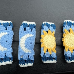 May include: Four crocheted pot holders with a sun and moon design. The pot holders are blue, white, and yellow.