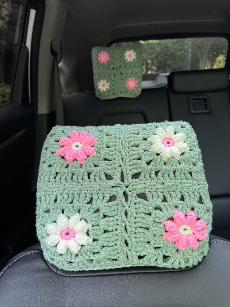 May include: Green crocheted car seat headrest with pink and white flower accents.