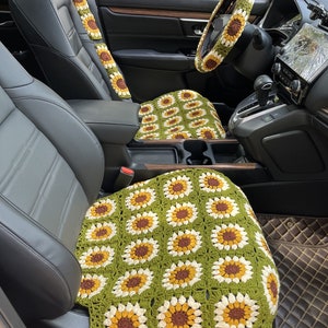 以下が含まれることがあります： 緑、白、茶色のクロシェのひまわりカーシートカバー。カバーは柔らかく、質感のある糸で作られており、ひまわりの繰り返しパターンが特徴です。カバーは車のフロントシートに表示されています。