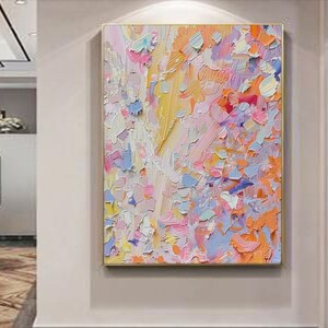 May include: Abstract oil painting with a gold frame. The artwork features a textured surface with a palette of pastel colors, including pink, blue, yellow, and orange. The brushstrokes create a dynamic and expressive composition.