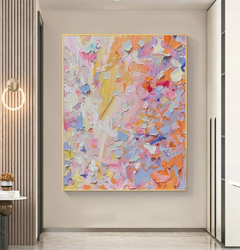 May include: Abstract oil painting with a gold frame. The artwork features a textured surface with a palette of colors including yellow, pink, orange, blue, and white. The brushstrokes are visible, creating a dynamic and vibrant composition.