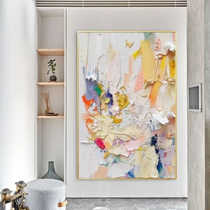 Op de afbeelding: Abstract schilderij met een witte achtergrond en kleurrijke penseelstreken in tinten roze, geel, blauw, groen en oranje. Het schilderij heeft een textuur en gelaagde uitstraling.