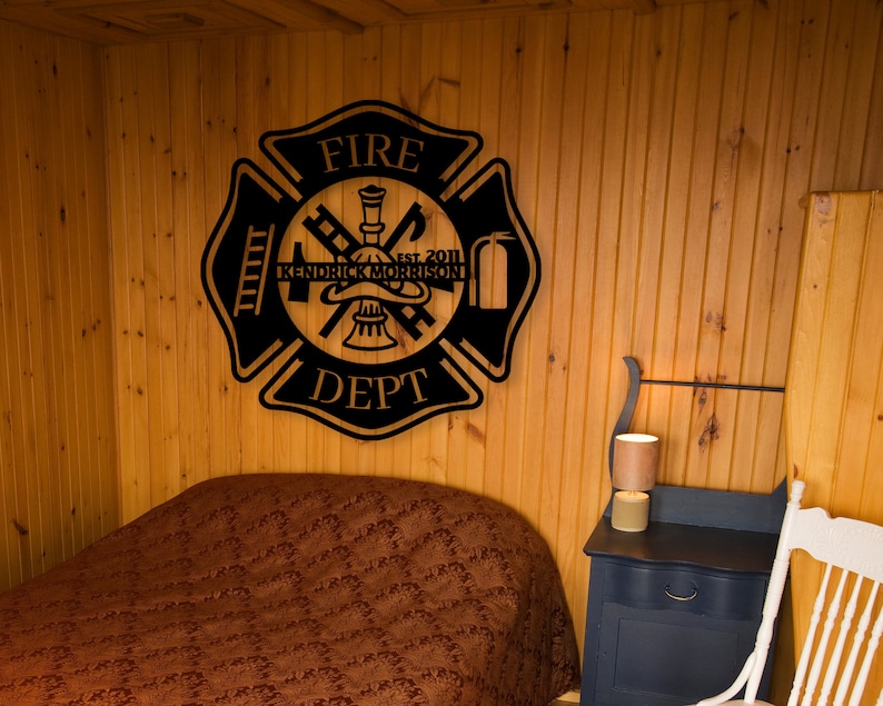 May include: Black metal fire department sign with the words "FIRE DEPT" and "EST. 2011" and the name "KENDRICK MORRISON" in the center. The sign is mounted on a wooden wall.