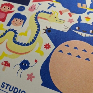 May include: A colorful illustration featuring characters from Studio Ghibli films, including Totoro, Kiki's Delivery Service, and Spirited Away. The illustration is printed on a white background and includes the text "Studio Ghibli" in black.
