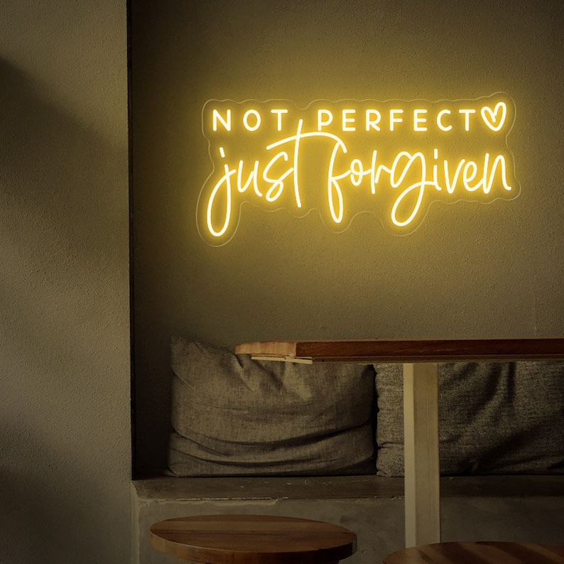 May include: A yellow neon sign with the text "NOT PERFECT just forgiven" and a heart symbol.