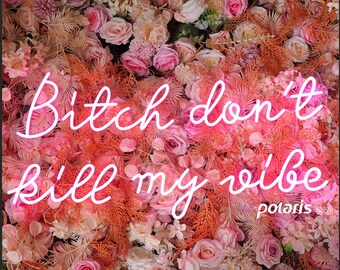 Puede incluir: Un letrero de neón con la frase "Bitch don't kill my vibe" en escritura blanca, sobre un fondo de flores y follaje rosas y melocotón. El letrero incluye la palabra "polaris" en la esquina inferior derecha.