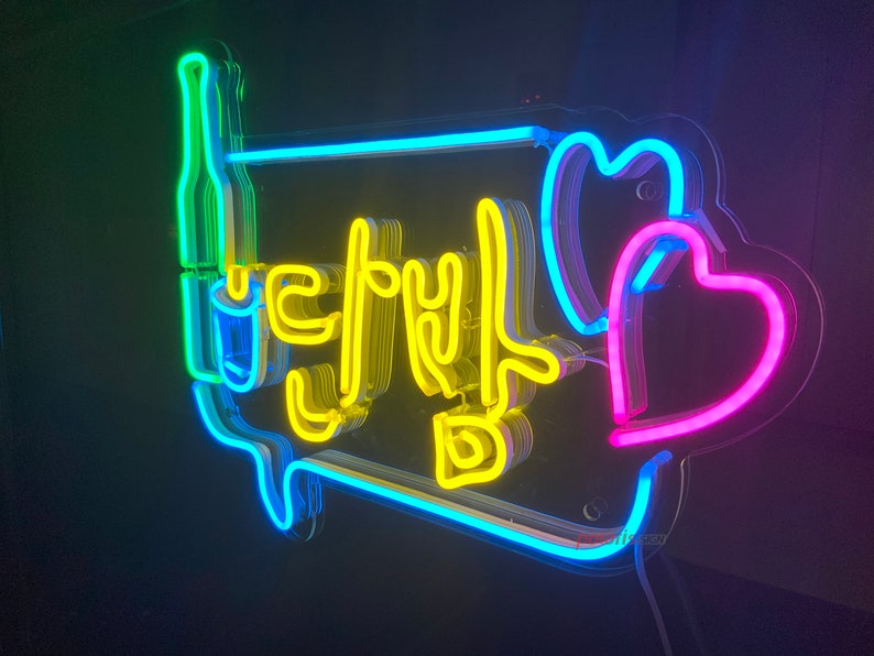 May include: Neon sign with the Korean word "Let's Drink" in yellow, surrounded by a blue outline. Two pink hearts are on the right side of the sign.