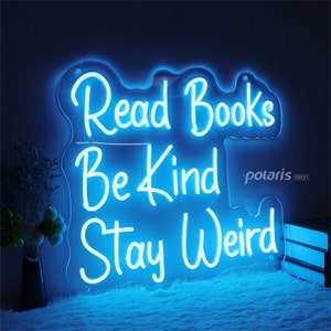 May include: Blue neon sign with the text "Read Books Be Kind Stay Weird".