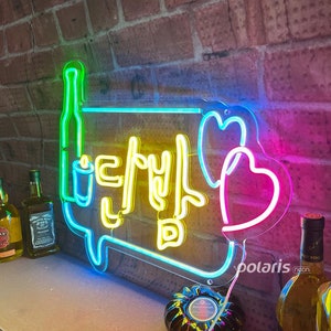 May include: Neon sign with a yellow speech bubble containing Korean text and a pink heart. The speech bubble is outlined in blue and green. The sign is mounted on a brick wall.