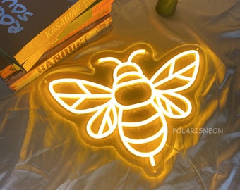 May include: A yellow neon light shaped like a bee with white outlines. The light is on and glowing. The text "POLARISNEON" is visible in the bottom right corner of the image.