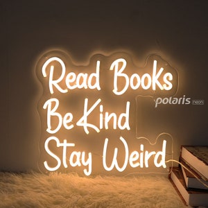 May include: White neon sign with the words "Read Books Be Kind Stay Weird" in a cursive font.