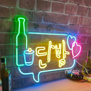May include: Neon sign with a green bottle, a yellow glass, and the Korean text "Let's Drink" in a speech bubble. Two pink hearts are on the right side of the sign.