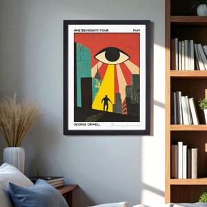 May include: Framed art print featuring a retro-style illustration. The artwork depicts a large eye with a beam of light shining on a silhouetted figure in a city. The title "Nineteen Eighty-Four" and author "George Orwell" are displayed.