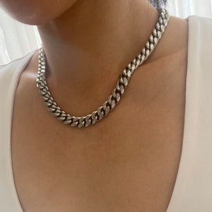 Könnte beinhalten: Eine silberne Curb-Kette mit einem dicken, massiven Gliederdesign.