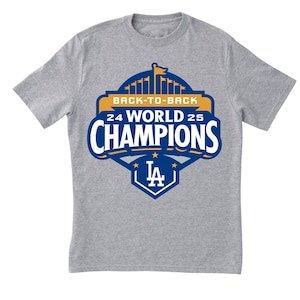 May include: A gray t-shirt featuring a blue and gold graphic with the text "BACK-TO-BACK 24 WORLD 25 CHAMPIONS" and the team's logo. The shirt is short-sleeved and made of a soft material.