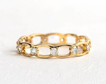 May include: A gold band ring with a delicate chain design and small clear stones set in the band.