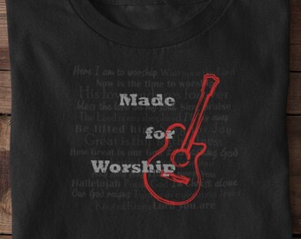 May include: Black t-shirt with a red guitar graphic and the text "Made for Worship" in white. The text is surrounded by other words in a smaller font.