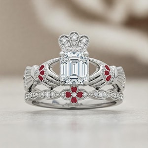 Peut inclure: Une bague de fiançailles en argent avec un grand diamant taille émeraude et un design de couronne. La bague est ornée d'accents de fleurs rouges sur la bande.