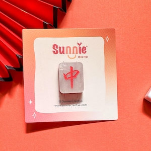 May include: A white ceramic tile with a red Chinese character on it. The tile is on a white card with the text "Sunnie Creative" and a website address.