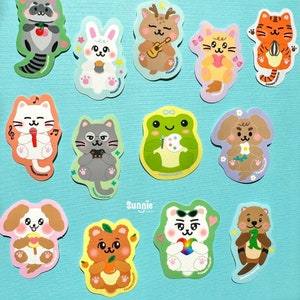 May include: A set of 12 colorful stickers featuring various animals, including a cat, dog, frog, deer, and otter. Each sticker has a unique design and features a cute cartoon animal with a fun activity. The stickers are perfect for adding a touch of whimsy to laptops, water bottles, journals, and more.