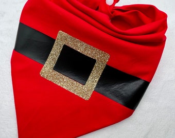 May include: Red fabric Santa Claus bandana with a black belt and gold glitter buckle. The bandana has a white button closure.