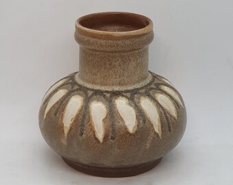 Könnte beinhalten: Eine kleine, braune Keramikvase mit einem weißen geometrischen Muster. Die Vase hat einen runden Körper und einen schmalen Hals.