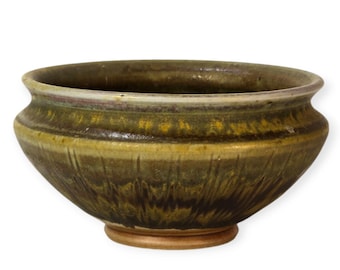 May include: A small, round, green ceramic bowl with a brown glaze. The bowl has a slightly flared rim and a rounded base.