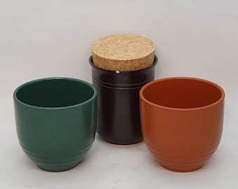May include: Three ceramic pots, one with a cork lid. The pots are green, brown, and orange.