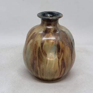 Peut inclure: Un petit vase rond en céramique avec un glaçage brun, bleu et blanc. Le vase a une large ouverture et un col étroit.