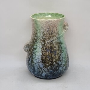 Peut inclure: Un vase en céramique vert, bleu et marron avec un motif ondulé et un bord festonné. Le vase a un glaçage unique et marbré.