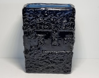 May include: A black ceramic vase with a textured surface. The vase has a rectangular shape and a light blue interior.