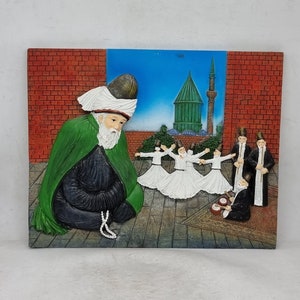 May include: A 3D wall art piece depicting a scene of a man in a green robe and white turban sitting with prayer beads, while a group of men in white robes perform a whirling dance in front of a mosque with a green dome.