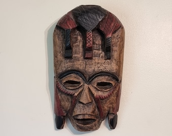 赤、黄、黒の顔料を使用した小さなアフリカの部族のマスク – 手彫りの