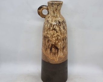 May include: A brown and white ceramic vase with a brown glaze and a handle. The vase has a mottled brown and white design.
