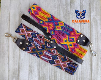 May include: Two pet leashes featuring intricate woven geometric patterns in vibrant pink, yellow, blue, and orange threads. Each leash includes dark brown leather accents, silver metal rivets, and a silver swivel snap hook. The logo Calavera Handmade for Pets is visible in the upper right corner.